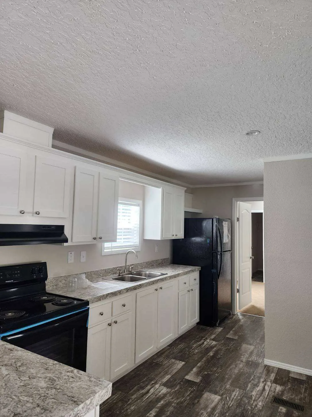 This kitchen features sleek white cabinets and modern black appliances, creating a contemporary and sophisticated look.